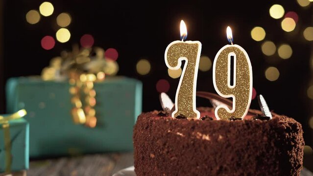 Birthday candle number seventy nine on a sweet cake on the table, 79th birthday. Fire from the lighter, blow out the holiday candle.