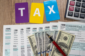 on the office desk are 1040 tax forms and new dollar bills to be filled out by a businessman.