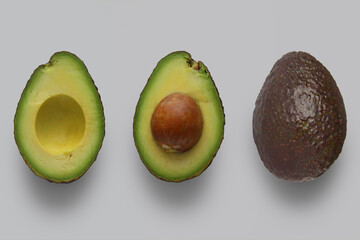 Avocado halves with pit and a whole avocado.