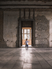 Backview of a young child walking towards a door in an extremly old building.