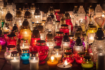 Colorful candles are burning on Polish cemetery during All Saints Day at night.