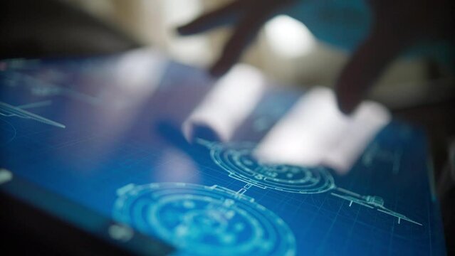 touch screen display device with information about technical specifications drawings and developments. a woman's hand flips through the information on the display, shot close-up