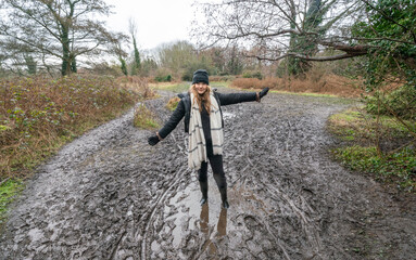 Woman walking in winter, stuck in the mud in wellington boots.