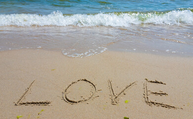 Inscription Love drawn on the sand. Concept of true and honest romantic feelings. spa novel on the...