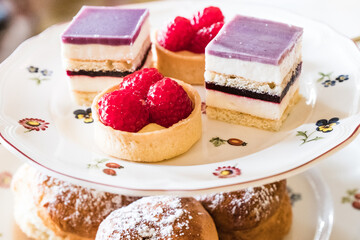 A rack of delicious English teashop cakes and sandwiches served for afternoon tea.