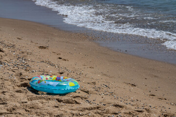 Child colorful inflatable ring or float life ring with swimming kickboard on sand beach, daylight on beach, sea wave