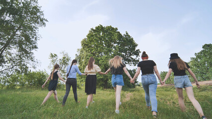 A group of girls are walking hand in hand outside the city.