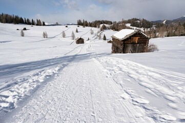 Traumhaft schön gelegene Almen auf den  winterlichen Armentara Wiesen am Heiligkreuzkofel in den Dolomiten während einer Winterwanderung 