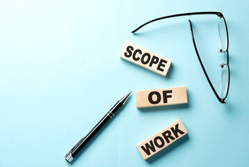 Text SCOPE OF WORK concept on wooden block on the blue background