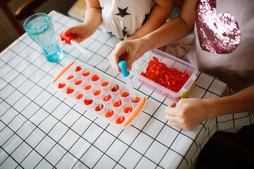 Funny children play with hearts and water at home in the kitchen. Educational classes and...