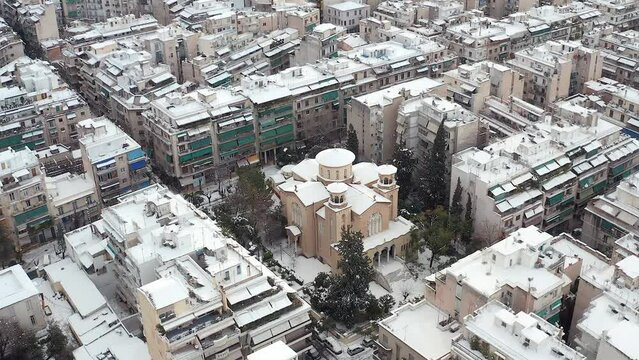 Aerial pullback Upward Aghia Zoni Orthodox Church covered in snow during winter, Athens Cityscape