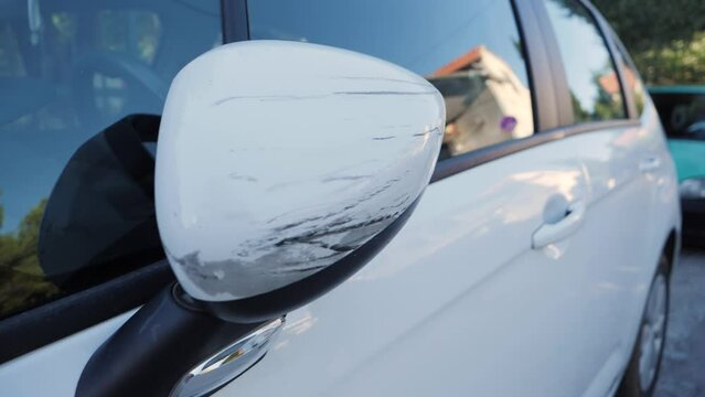 Scratched white car side mirror