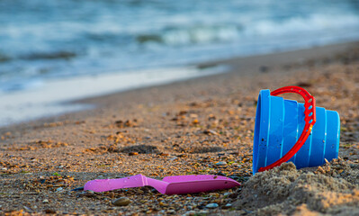 Children's toys on a sandy beach, blue sky and the sea in the background