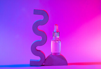 Bottle of cosmetic serum in neon light