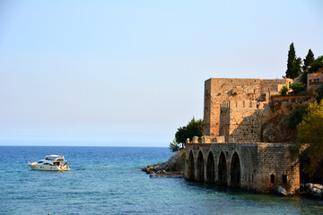Fototapeta na wymiar ancient fortress on the shore of mediterranean sea with boat, Turkey Alanya