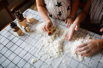 Funny children play with artificial snow at home in the kitchen. Educational classes and...
