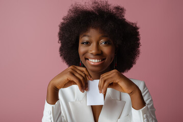 Happy smiling African American woman, model wearing elegant jewelry, classic shirt, holding small white paper bag, box, posing in studio, on pink background. Copy, empty space for text