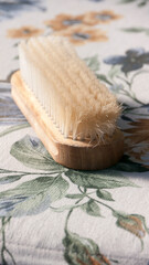 Fototapeta na wymiar Cepillo para ropa de madera con cerdas blancas sobre tela con estampado floral