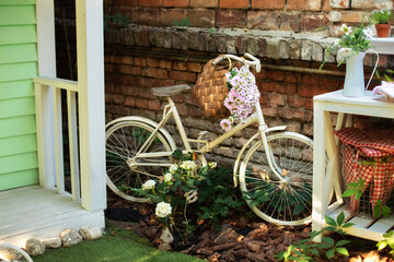 Fototapeta na wymiar Decorative white vintage bicycle against brick wall. Old bicycle parked against a stone wall in garden. Street decoration backyard. Autumn garden corner. Patio of house with garden plants and bicycle.