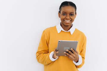 Happy black student girl in a yellow jacket holds a tablet and shows cheers on a white background