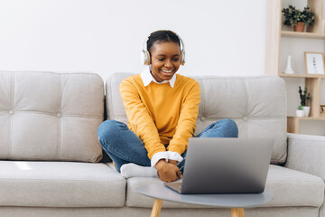Young African American woman talking on video call in living room at home, distance learning concept from home.