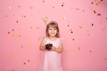 Obraz na płótnie Canvas Funny child girl in dress with birthday cupcake with candle on pink background