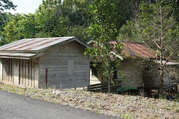 photo of a house by the side of the road, a building used to sell goods in the countryside, the photo was taken in the morning and the house is still closed, made of wood and a tin roof