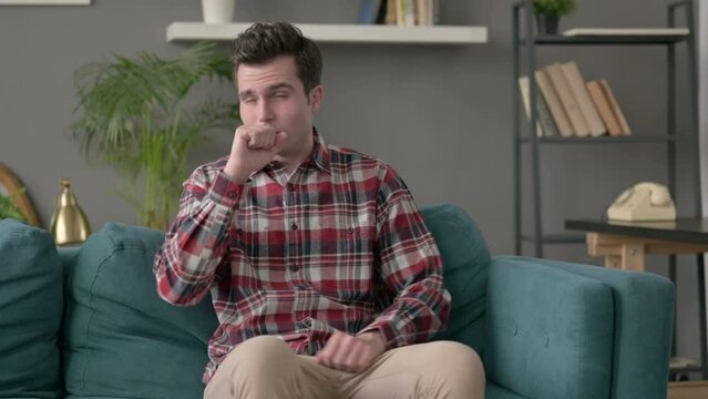 Man Coughing while Sitting on Sofa 