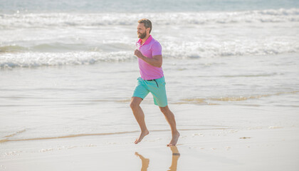 mature athletic man running on summer beach for training, achievement