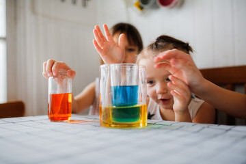 Caucasian kid girl play in the kitchen at home with colored liquids. Experiments with color at home.