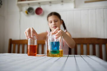 Caucasian kid girl play in the kitchen at home with colored liquids. Experiments with color at home.