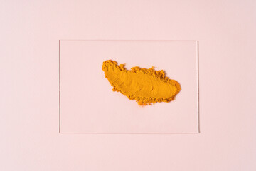 Beautiful smear of orange turmeric spread on a glass on a pastel beige background. Photography in flat lay style.