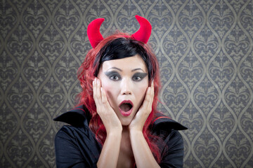 Girl in Evil Costume is in Shock Against Vintage Wallpaper