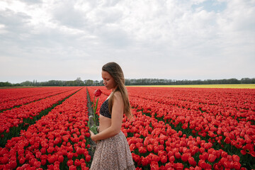 Caribbean girl in a flower field full of red tulips in the Netherlands