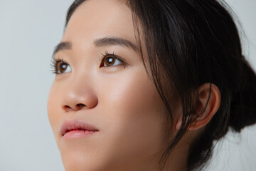 Close-up portrait of dreamy, beautiful girl looking away, posing isolated over gray studio background