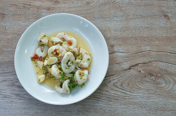 Thai spicy and sour steamed slice squid salad in lemon sauce on plate