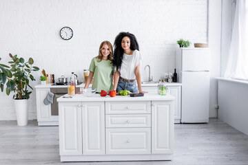 happy multiethnic lesbian couple standing together in modern kitchen.