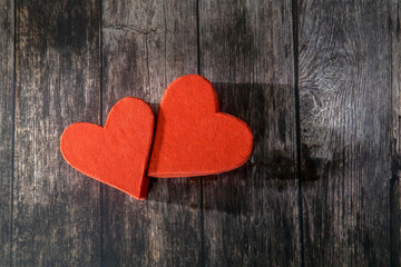 Obraz premium Two red paper hearts are next to each other on a wooden brown table. The day of Valentine. Copy space