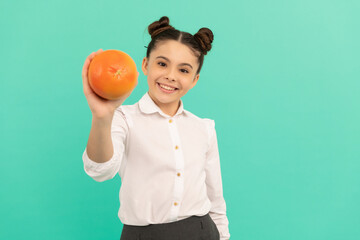 smiling school kid with grapefruit on blue background, dieting