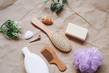 Natural organic bio cosmetics, bath products set flat lay photography. White shampoo bottle, wooden comb, purples sponge, seashells and green leaves. Personal care concept beauty photo
