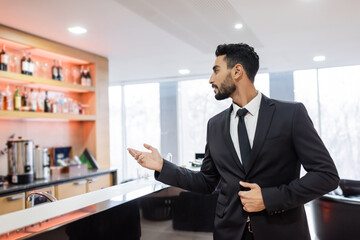 young mixed-race guard pointing with hand near blurred lobby bar.