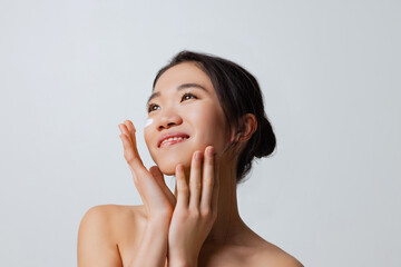 Cropped portrait of young beautiful woman doing skincare routine, moisturizing face with special cream