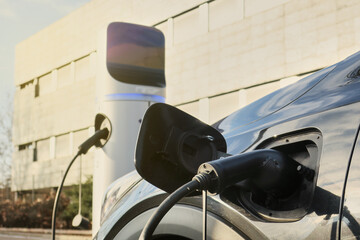 Green mobility concept. Power cable plugged from charging unit to electric car of EV vehicle