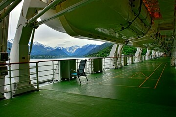 Meeresbucht mit Bergen im Hintergrund und Schiffsreling mit unterseite eines Rettungsboots von...