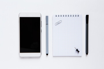 Flat lay with notebook, phone, pens on white background. Business office or planning concept. Copy space for text.