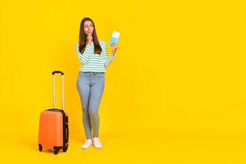 Full body photo of young woman hand touch chin thoughtful minded look empty space tourist isolated over yellow color background