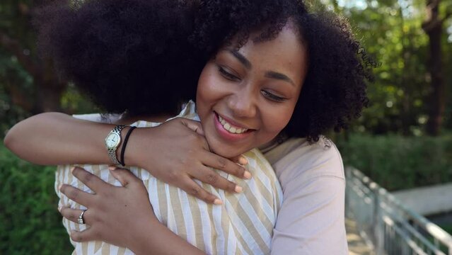 Slow motion happy young woman hugging friend in the park