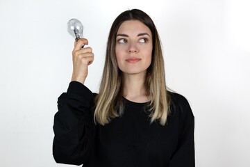 Photo of young girl happy positive smile hold light bulb idea genius think isolated over gray background.	