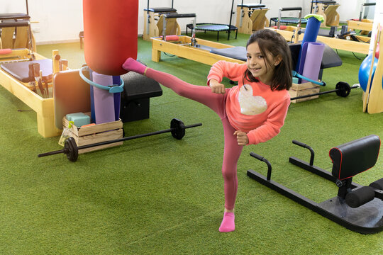 little girl practicing self defense and martial arts, kicking the punching bag in the gym