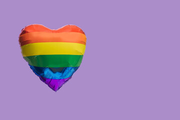 A rainbow color heart shaped balloon with copy space. Very peri background. LGBT liberation...